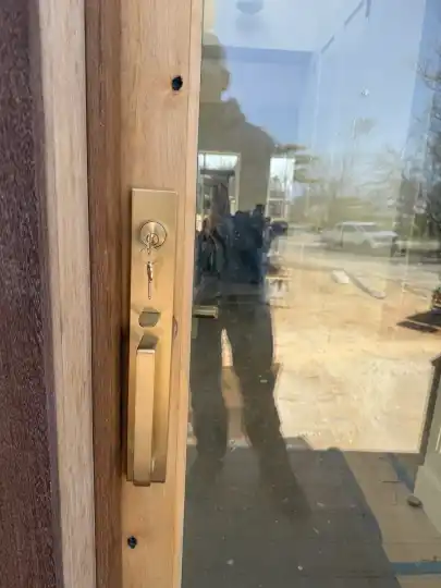 Satin brass Emtek handleset installed on a wood and glass door in Baiting Hollow